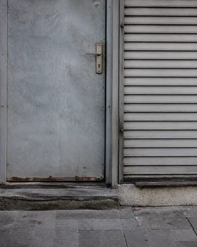 Puerta metálica de un local comercial con cerradura vista, sin rótulos de marca.