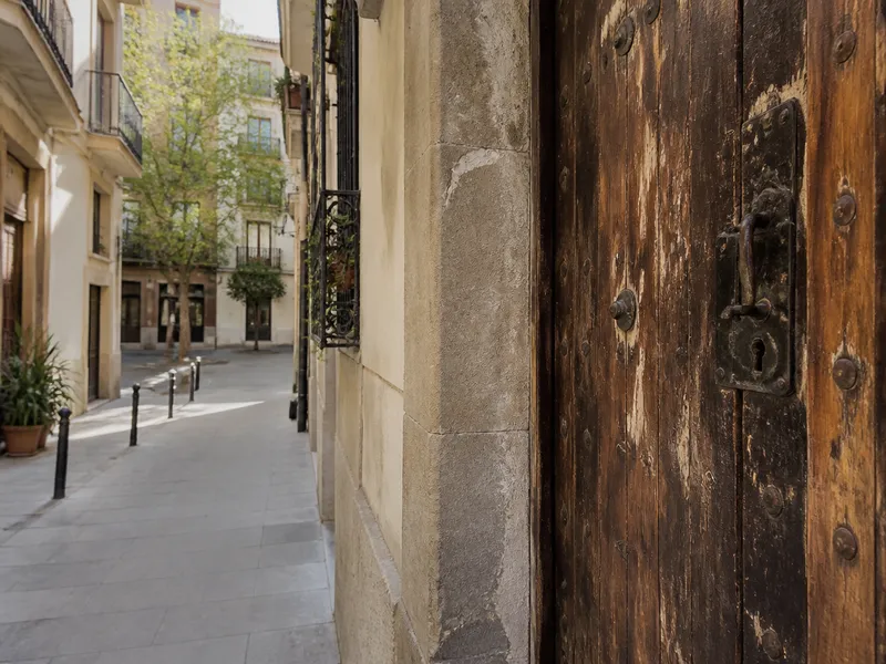 Puerta de madera antigua en una calle estrecha de Gràcia, cerradura vista, sin personas.